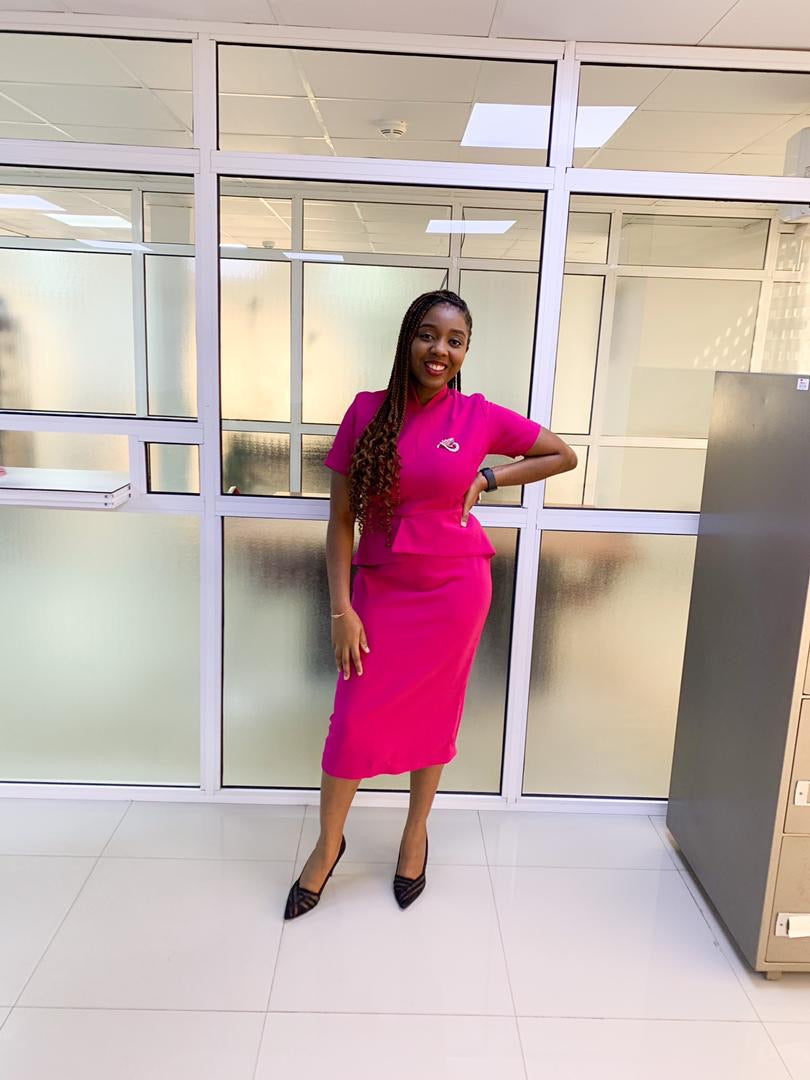 Woman in tailored pink dress with brooch posing in modern office setting
