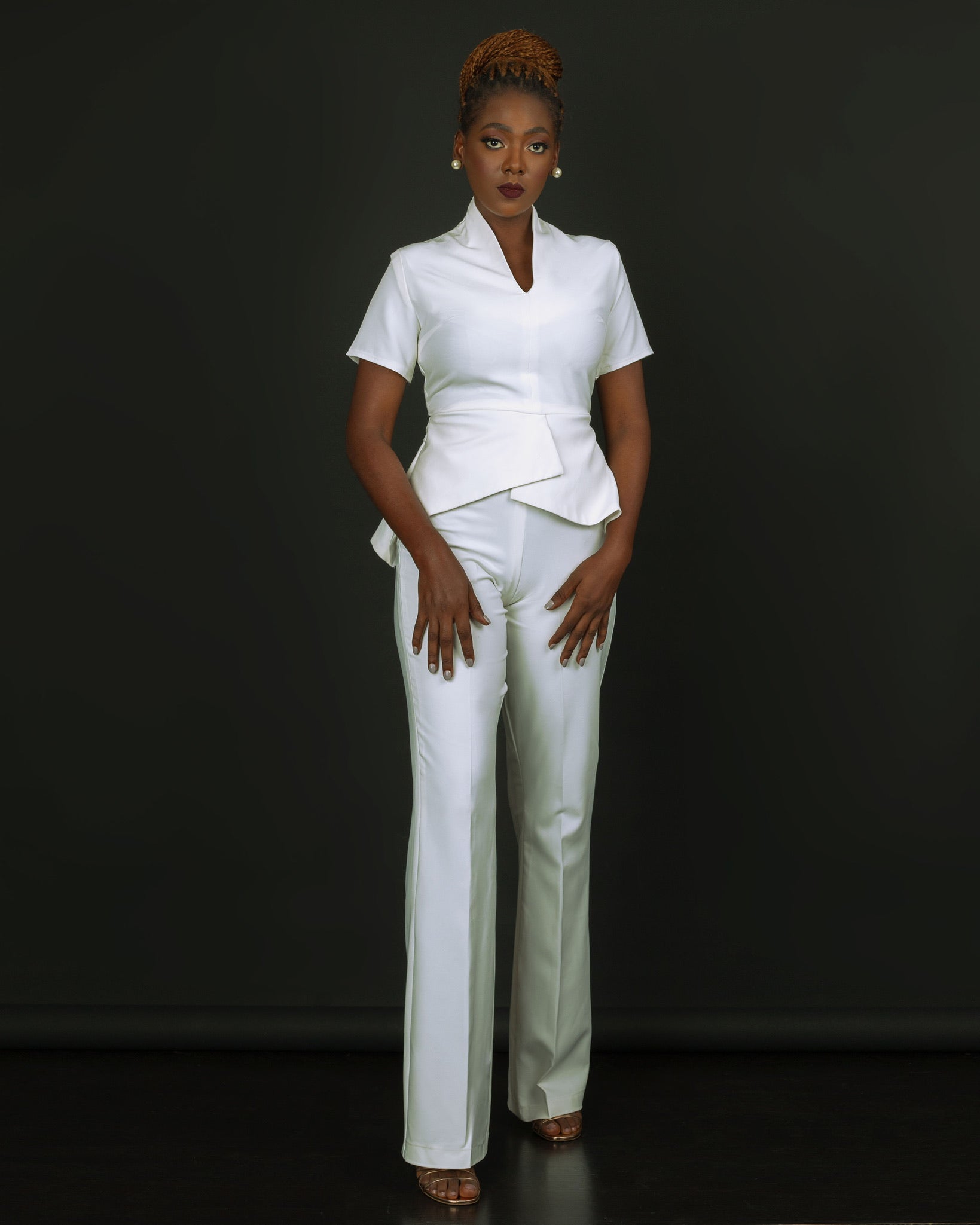 Woman modeling tailored white pantsuit on black background, modern fashion outfit